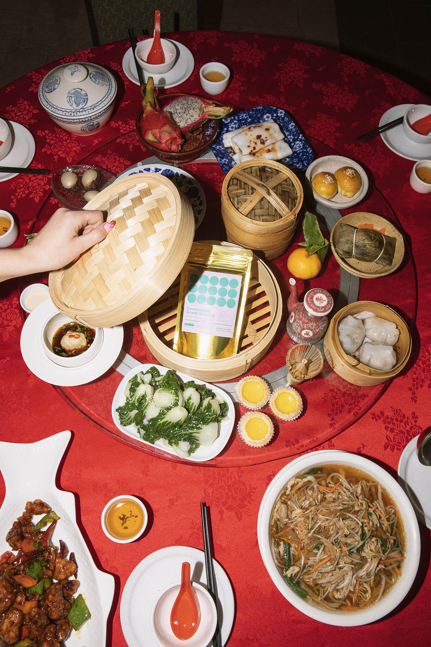 A dim sum table with a bamboo steamer in the middle reveals a 100 gram pouch of matcha when the lid is removed.